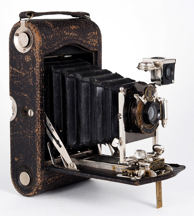 Две фотокамеры: 1. Форматная фотокамера с тремя кассетами и объективом. Западная Европа. 2. Раскладная компактная фотокамера под широкую рулонную пленку 90 мм. США, компания «Eastman Kodak». Конец XIX — начало ХХ века. Дерево, латунь, оригинальный кофр.